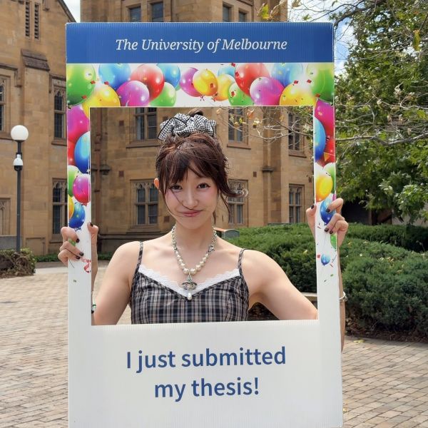 Smiling student holding instagram style thesis submission frame